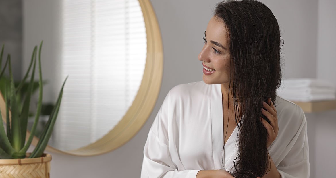 Mulher caucasiana mostra como usar óleo de cabelo corretamente para garantir a saúde de seu cabelo